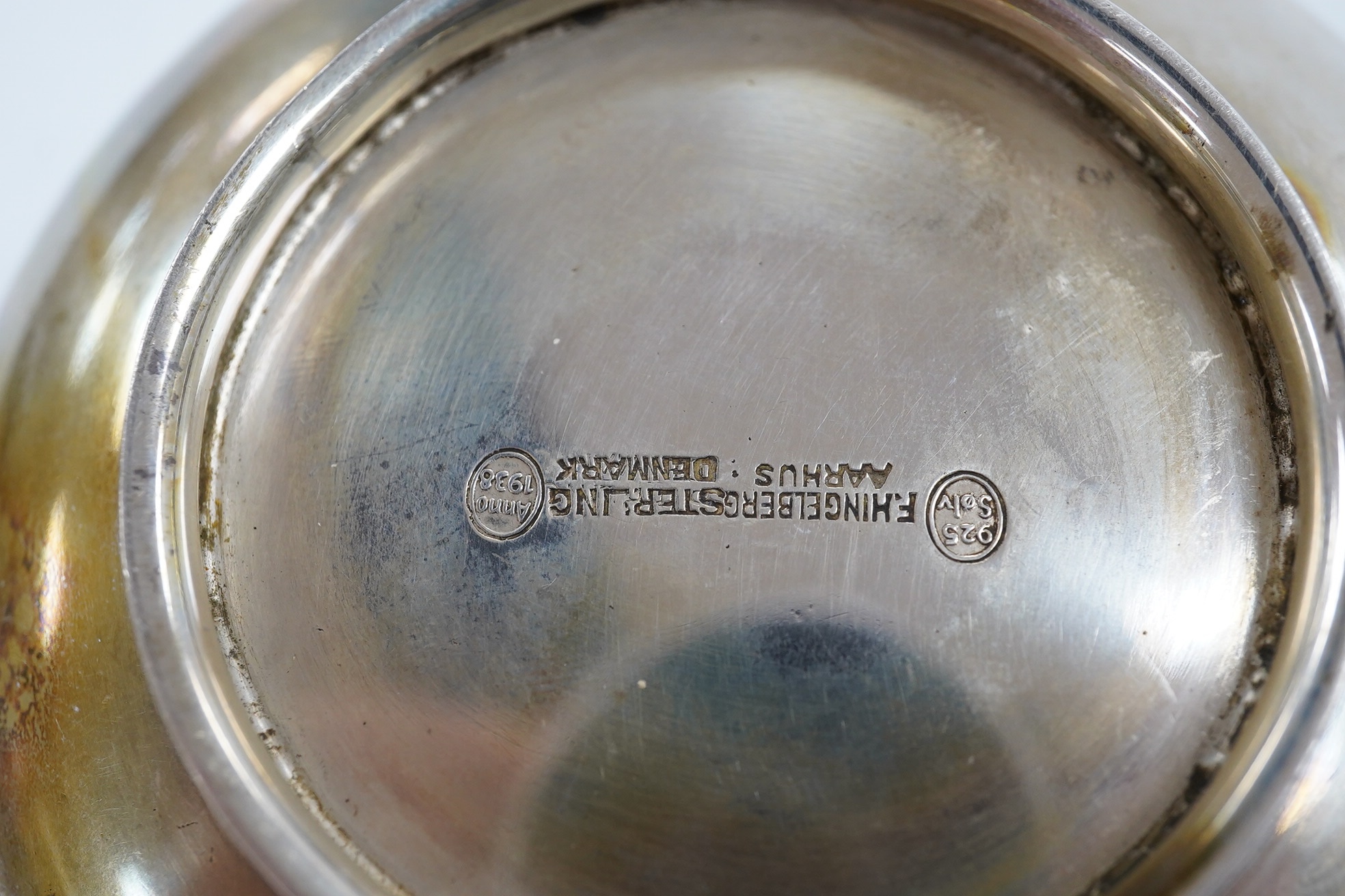 A Danish sterling saucepan, with wood handle, by F. Hingelberg, diameter 95mm and a pair of French pierced plated serving tongs. Condition - poor to fair